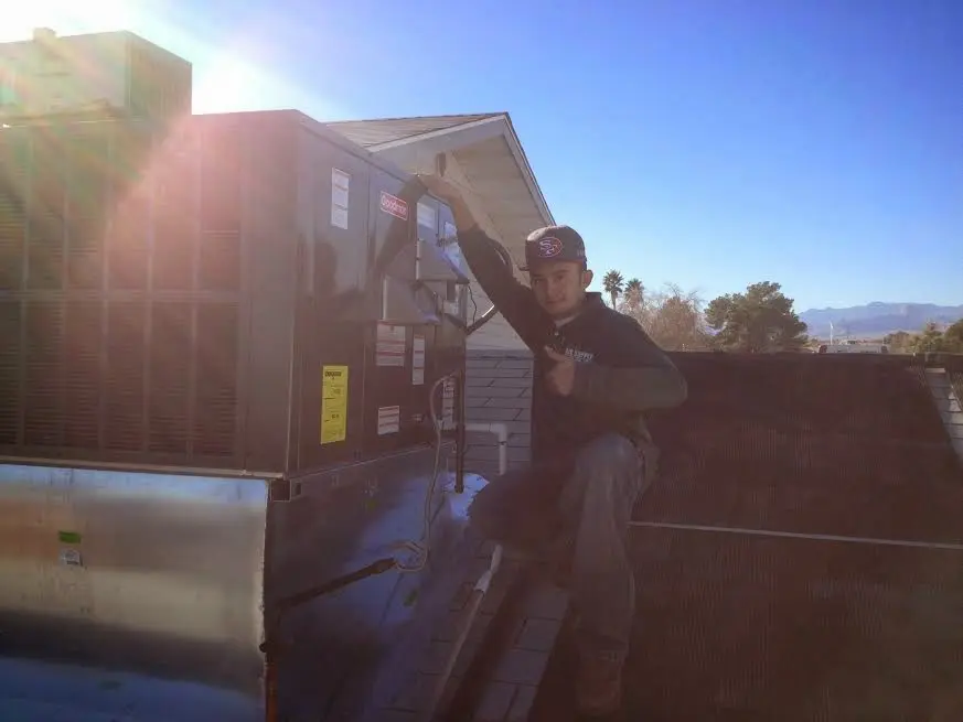 HVAC technician performing Air Duct Cleaning on a rooftop unit in Hayward